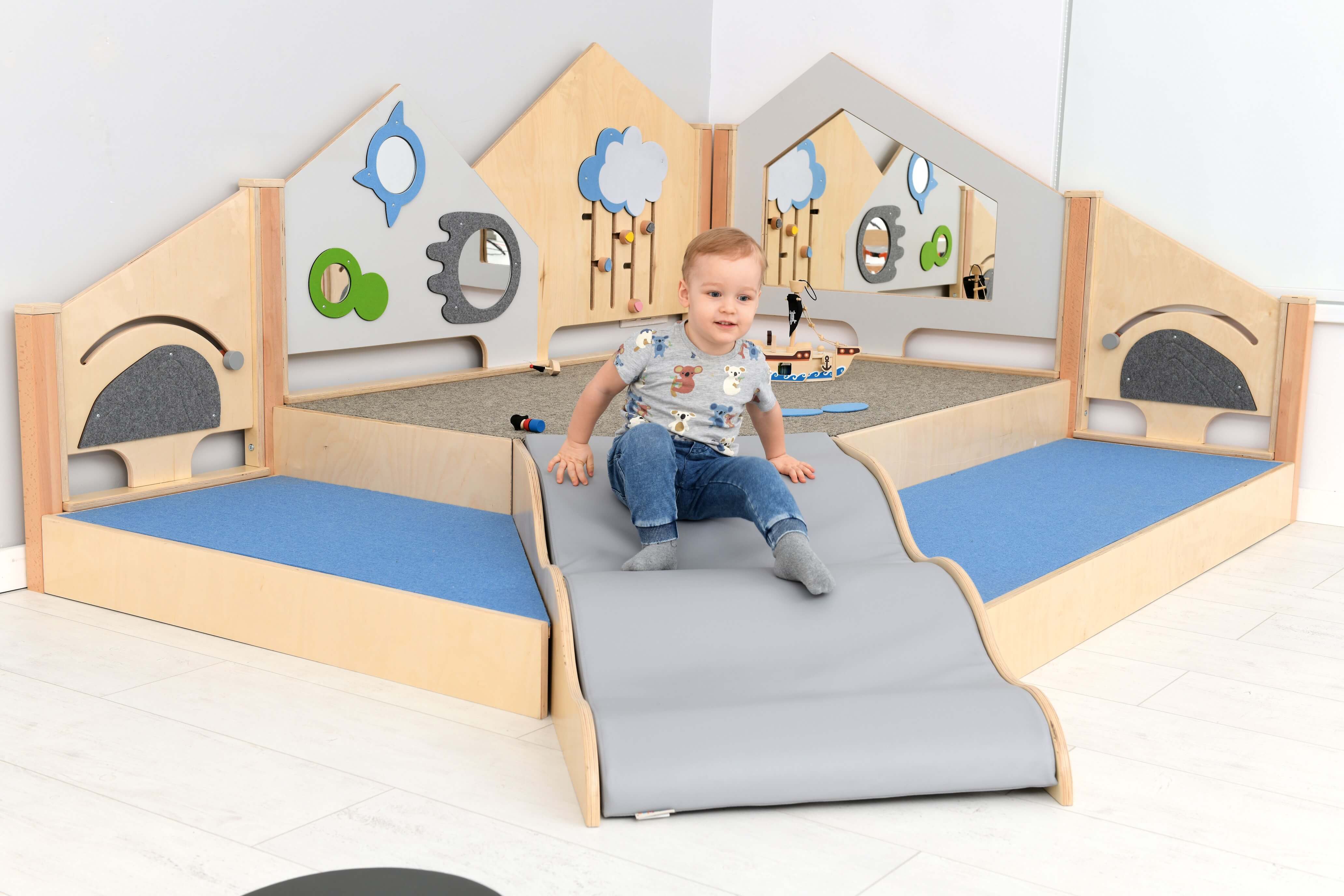 Kindergarten Spielpodest Saphir 2 im Gruppenraum Krippenkind rutscht