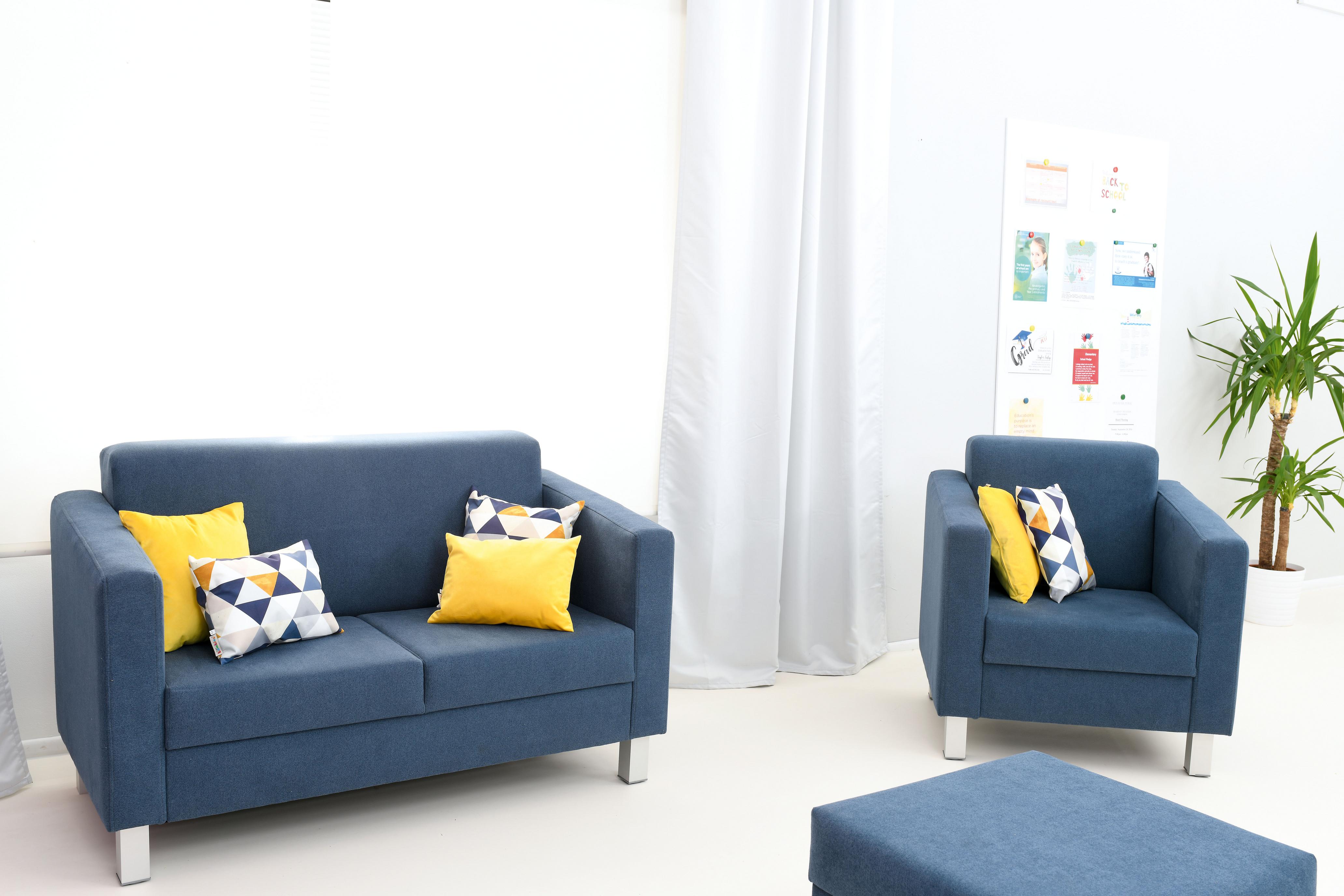 Gelbe Kissen auf blauen Möbeln im Gruppenraum.