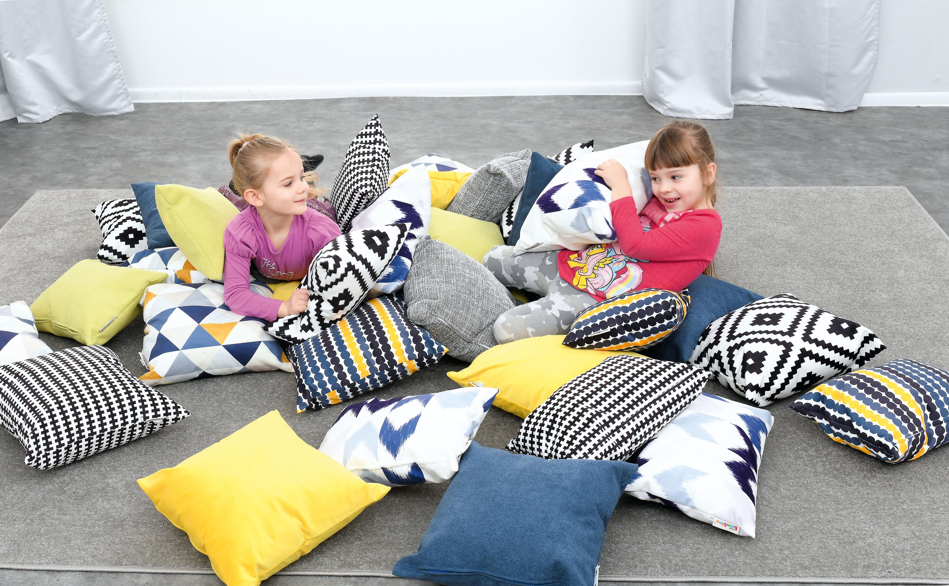 Kinder spielen mit Kissen für Sitzlandschaft, lachend.