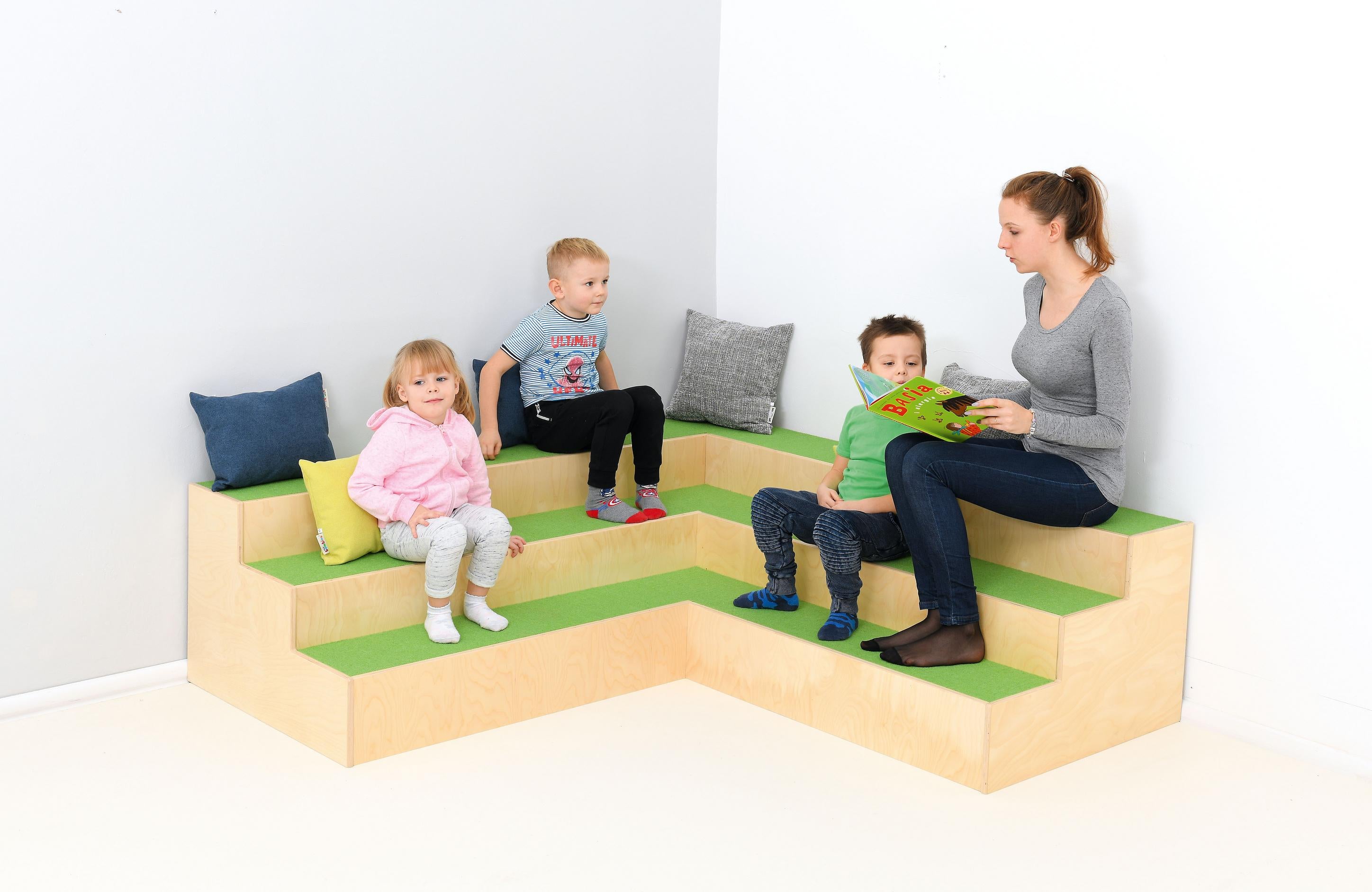 Stufenpodest-Sitzecke mit Kindern und einer Vorlesesituation.