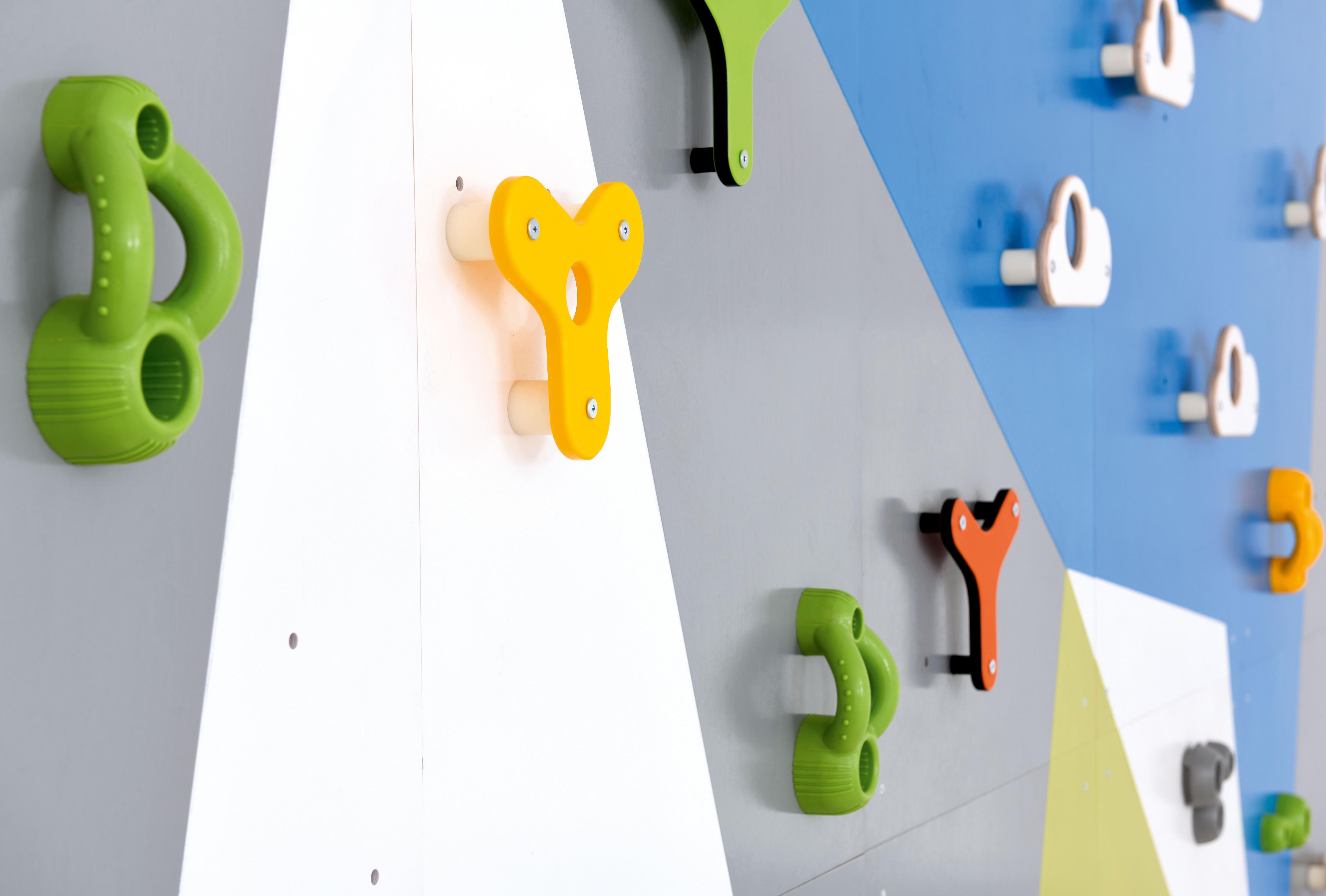 Bunte Kletterwand mit farbigen Griffen in Sporthalle/Kita.