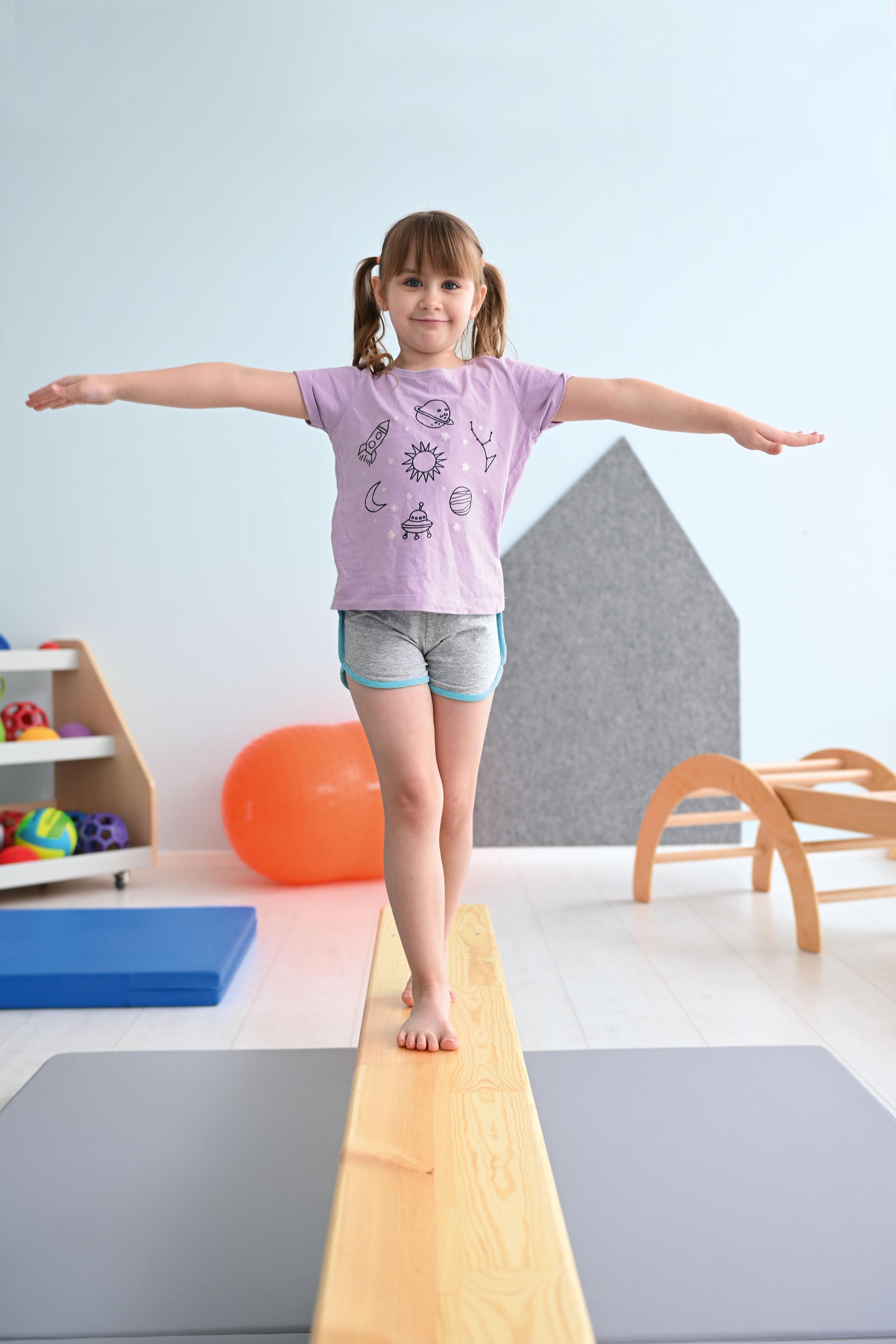 Kind balanciert auf Turnbank 3 m im Gruppenraum.
