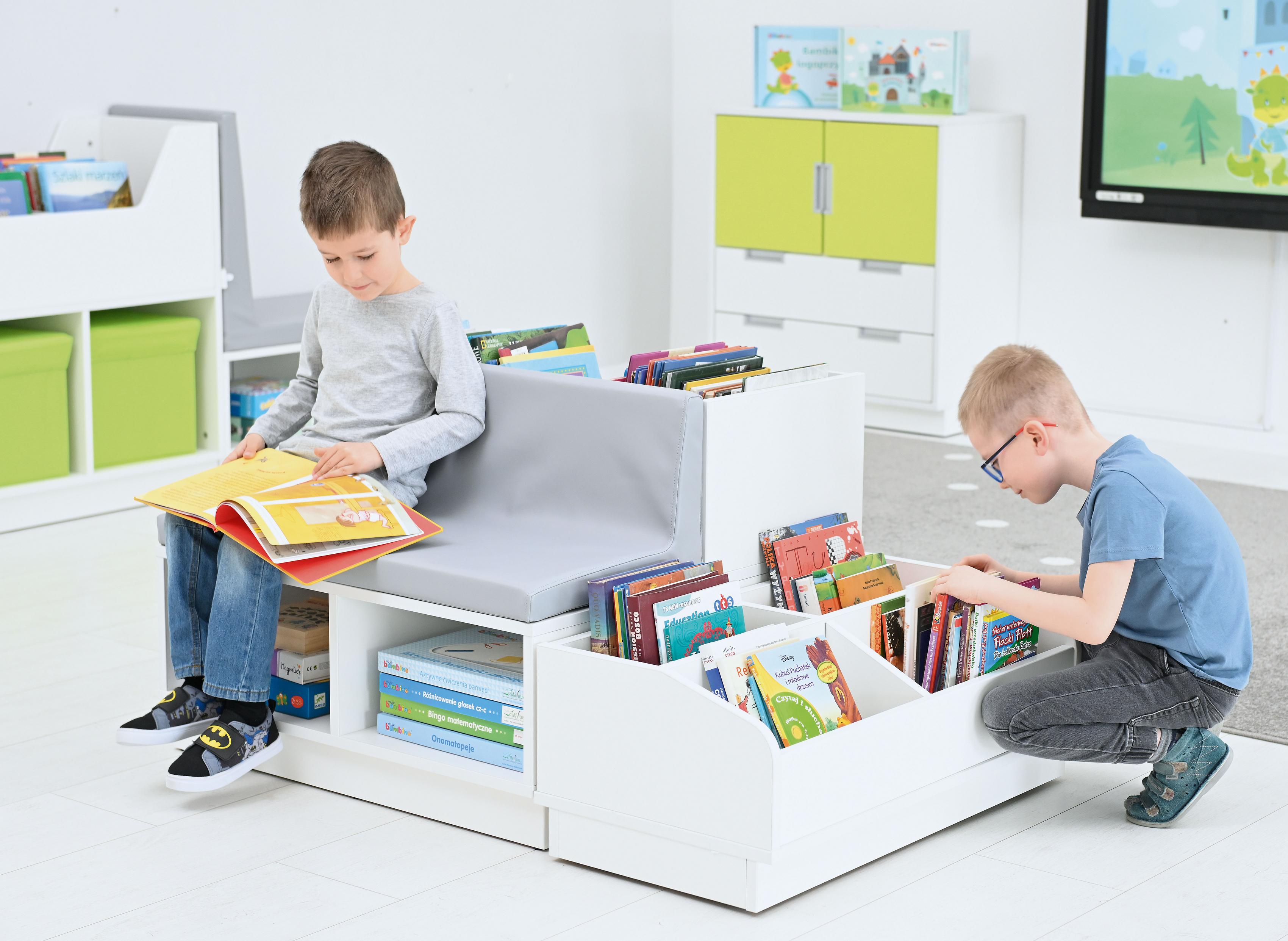 Kinder lesen auf einer Bücherbank in der Leseecke. - Produkt wird im Kindergarten oder Schule genutzt.