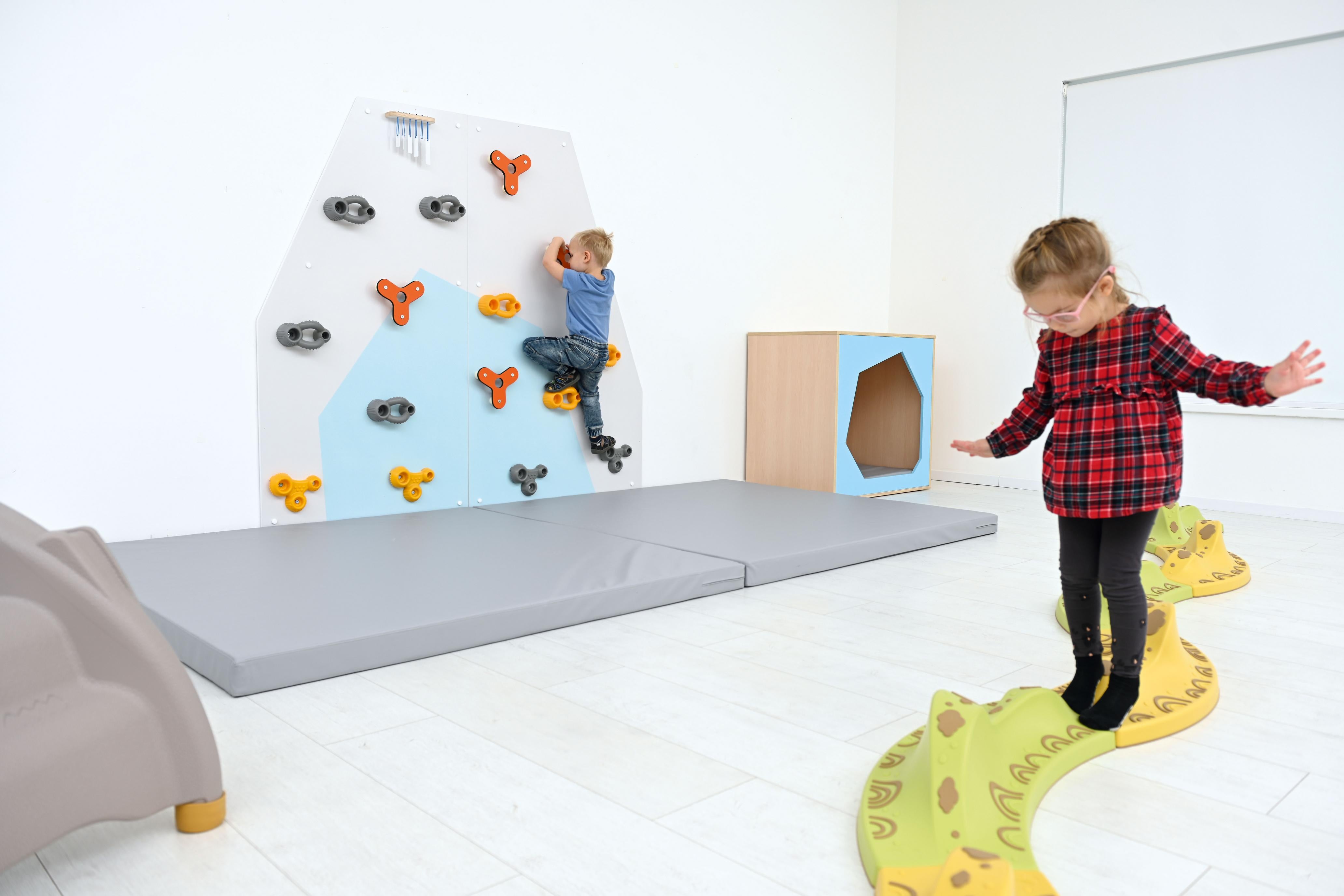 Kinder spielen an bunter Kletterwand für Kita.