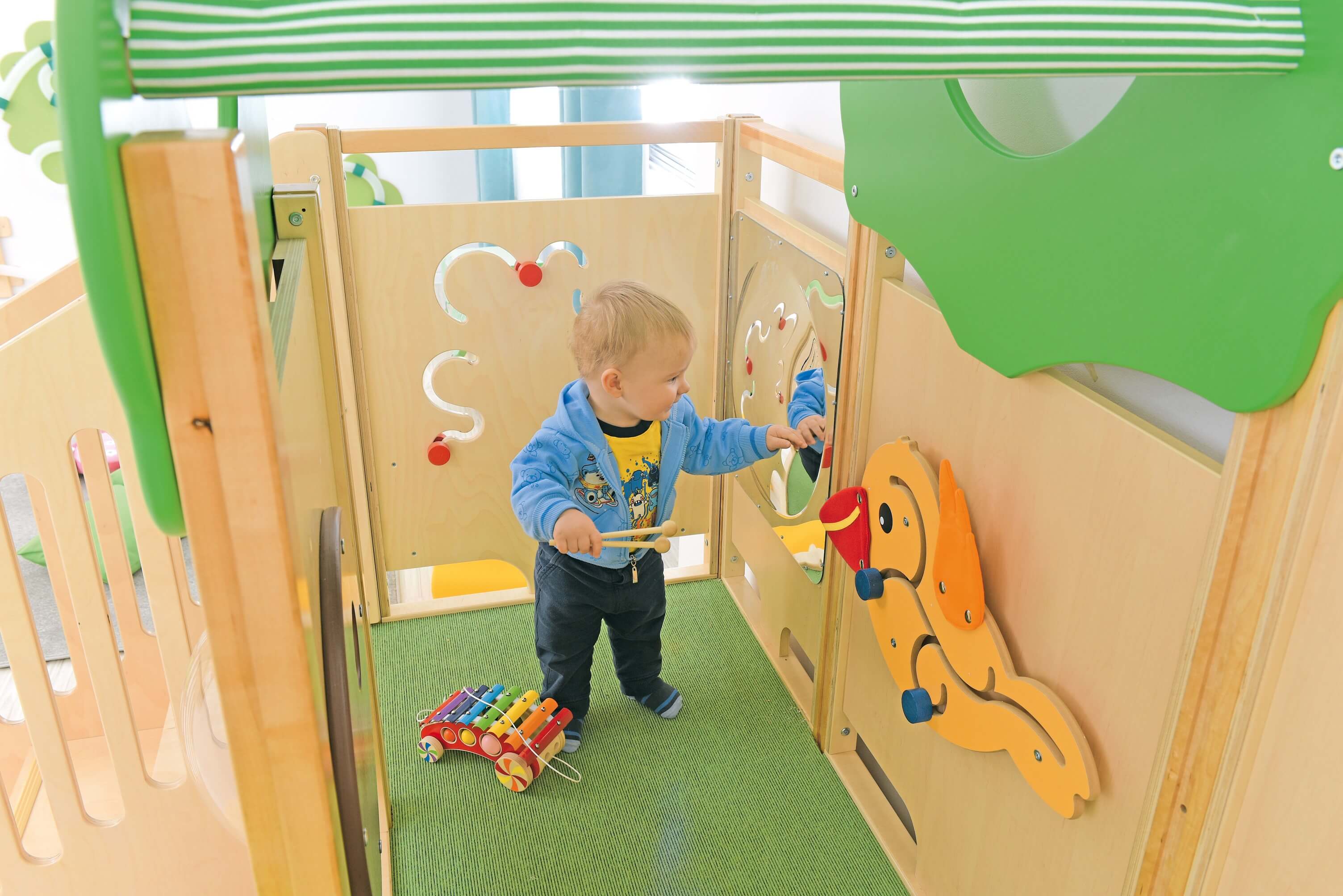 Kindergarten Spielpodest Vogelnest Kind schaut in den Spiegel