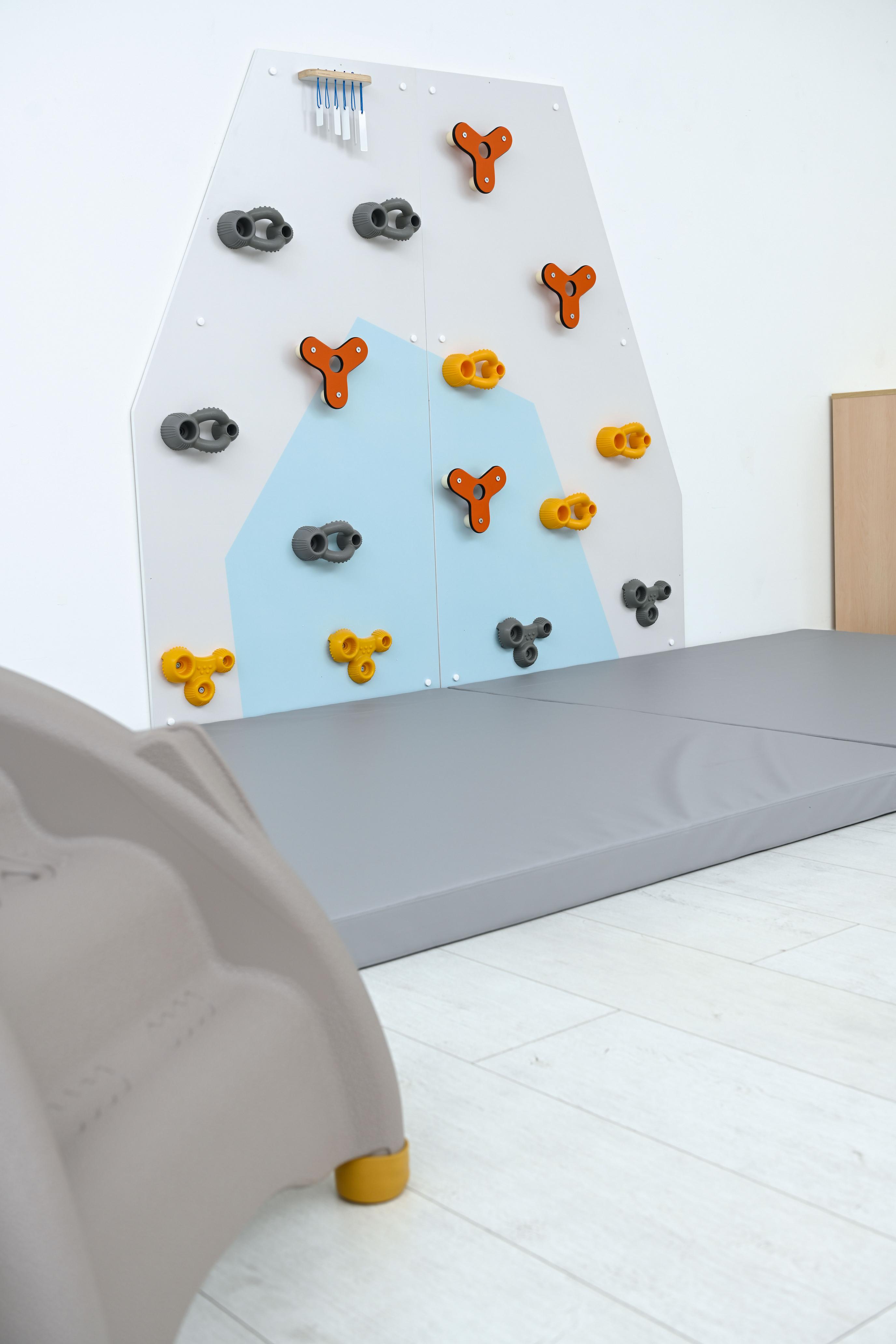 Kletterwand für Kita mit bunten Griffen und Matte.