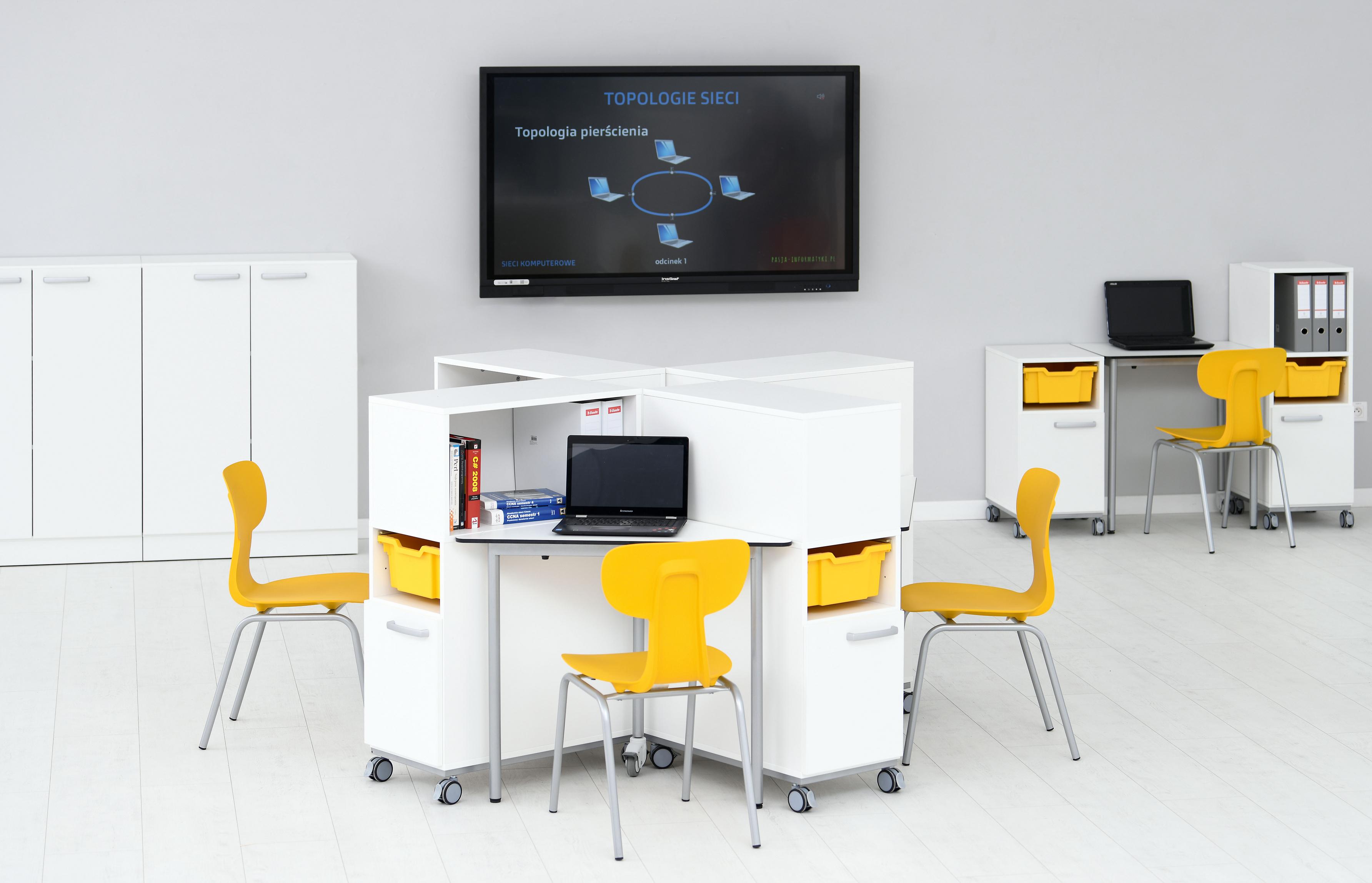 Schülerstühle in Konferenzraum mit Laptops und Tischen.