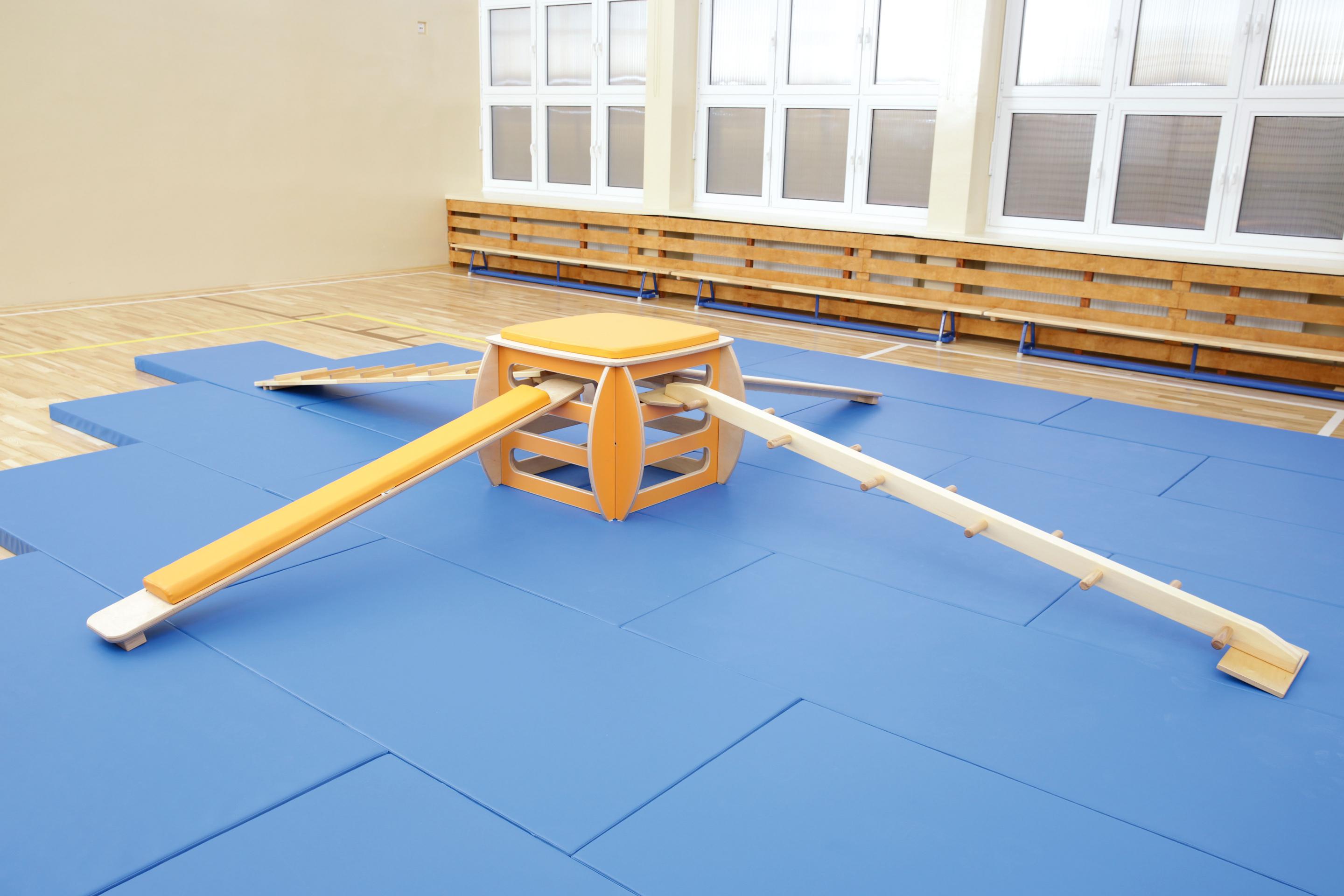 Turnpodest mit Balancierparcours auf blauer Gymnastikmatte.