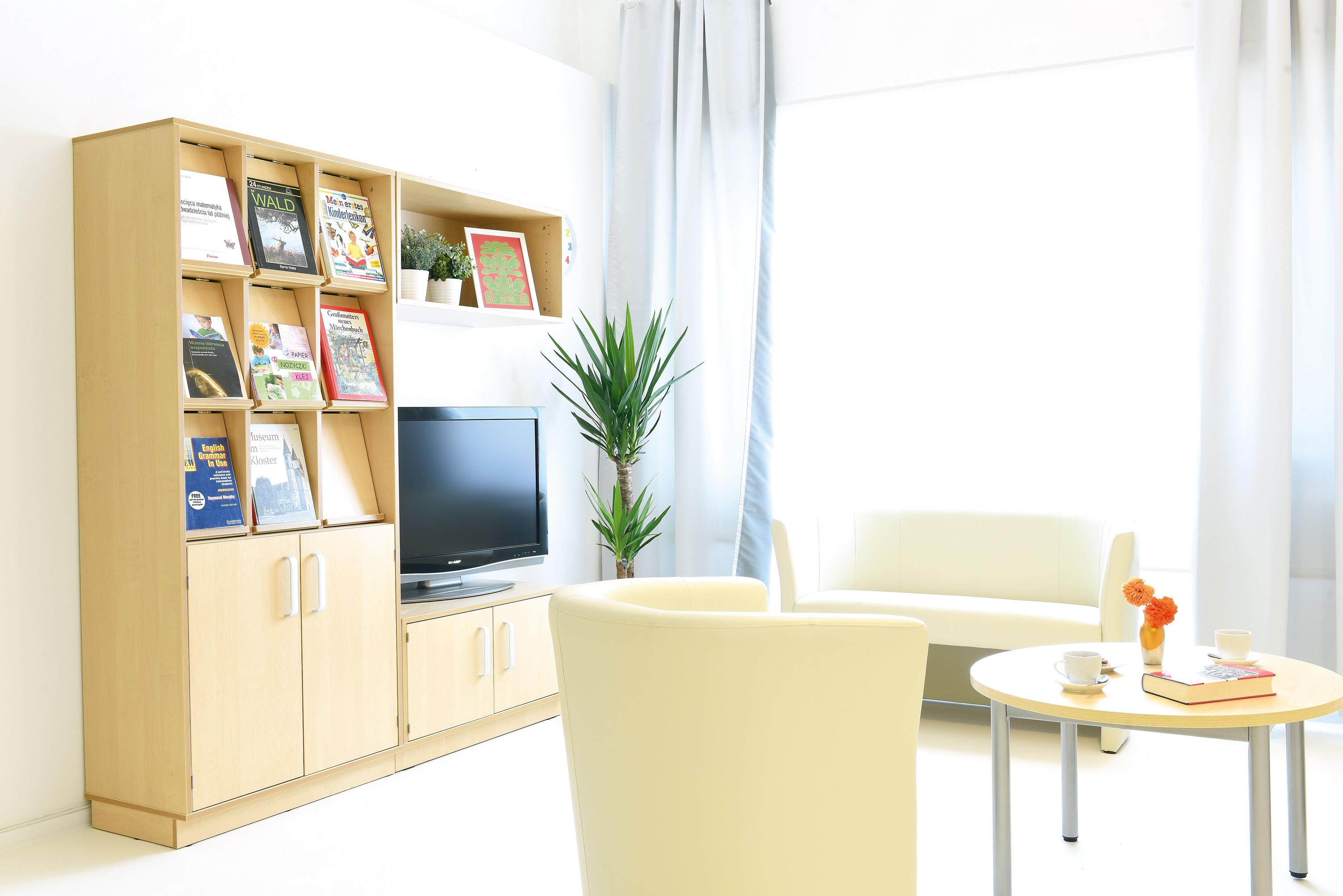 Zeitschriftenregal mit Schrank neben gemütlichem Sitzbereich. - Produkt wird im Kindergarten oder Schule genutzt.